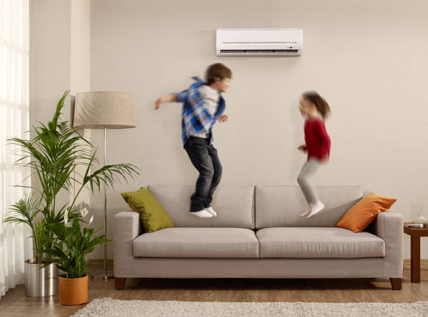 Kids jumping on a sofa Kids playing in a modern house and jumping on sofa air conditioner family stock pictures, royalty-free photos & images