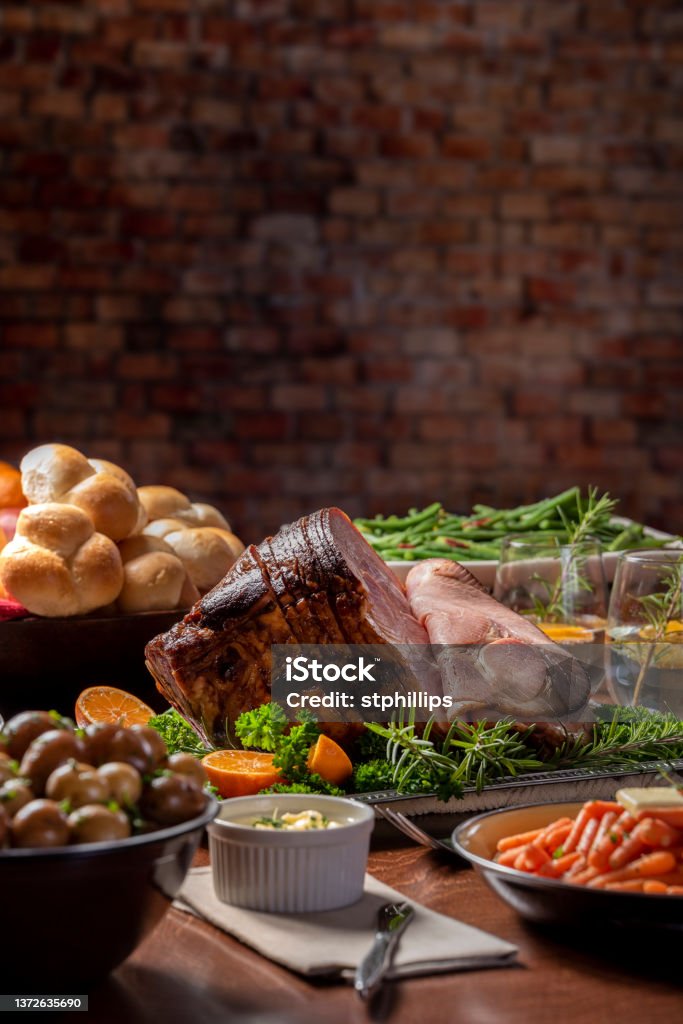 Glazed Spiral Cut Easter Ham Dinner Holiday baked spiral cut ham with all the side dishes, carrots, green beans, potatoes and dinner rolls. Easter Stock Photo