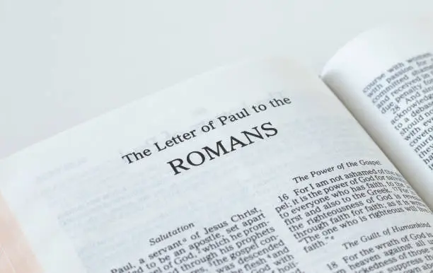 Romans open Holy Bible Book isolated on white background. A close-up. New Testament Scripture. Studying the Word of God Jesus Christ. Christian biblical concept of faith, hope, and trust.