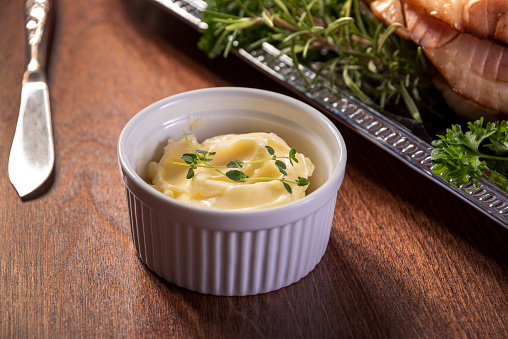 Small bowl of thyme infused butter. Butter knife is in the background.