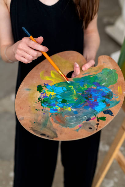 istock Painter artist stands in studio holding brush and palette with mixed paints in hands 1372638229