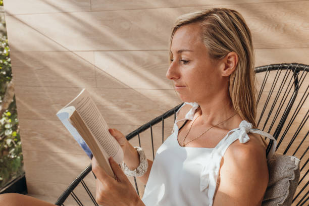 istock Young woman reads a book on a balcony 1372641984
