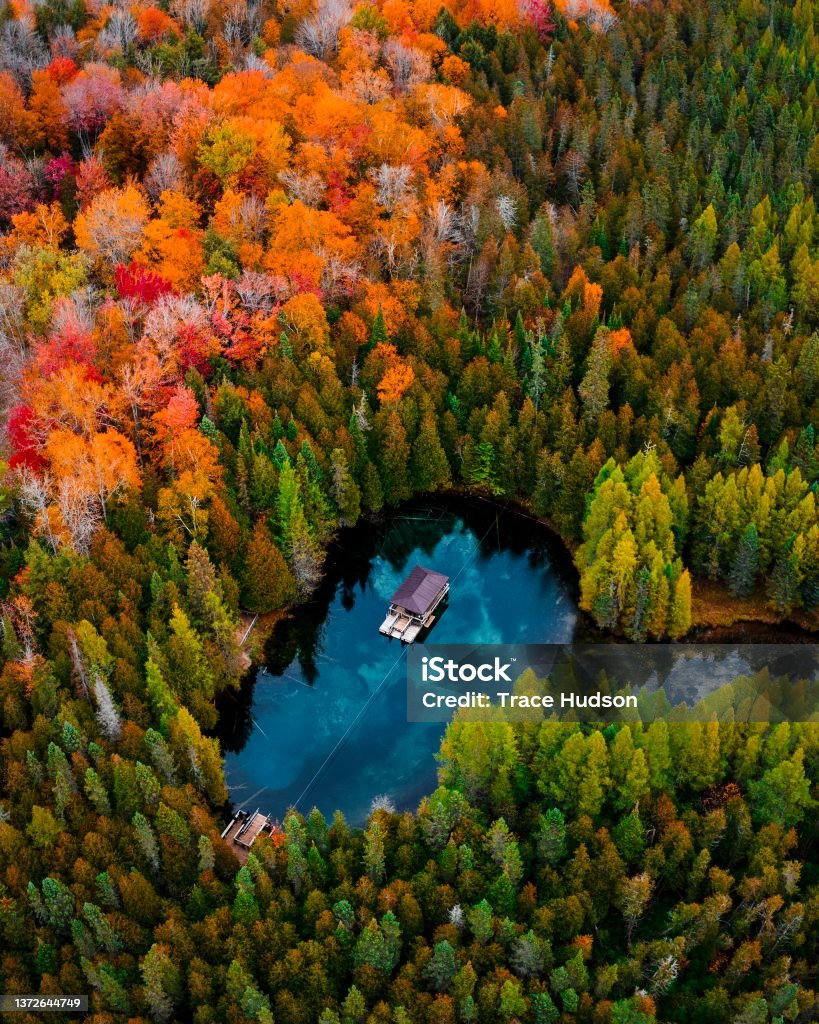 Kitch-iti-kipi Freshwater Spring in Upper Peninsula Michigan Drone/Aerial image of Kitch-iti-kipi, a freshwater spring in the Upper Peninsula of Michigan. This was taken during a roadtrip in the fall of 2019. The fall colors were starting to change creating a beautiful scene to photograph. Autumn Stock Photo
