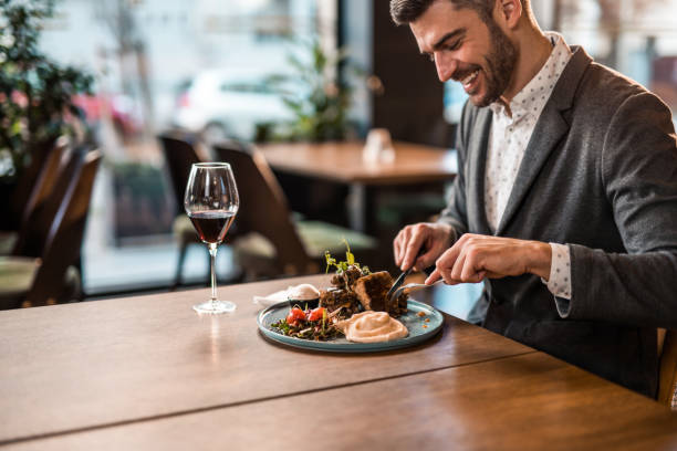istock Happy young man eating lunch at a restaurant. 1372644828