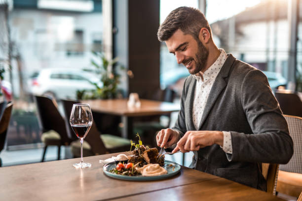 Happy young man eating lunch at a restaurant. stock photo