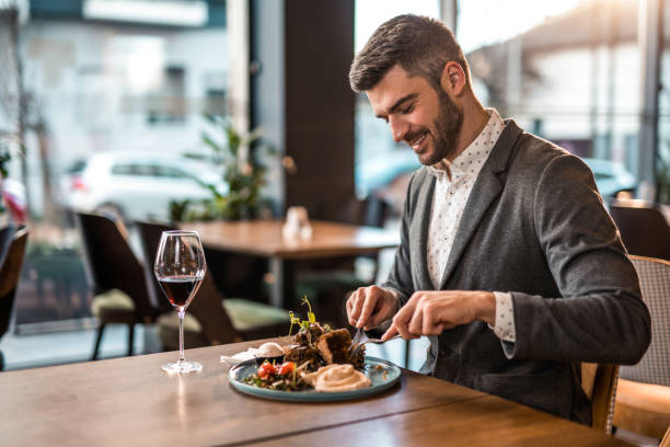 szczęśliwy młody człowiek jedzący lunch w restauracji. - restaurant dinner dining gourmet zdjęcia i obrazy z banku zdjęć