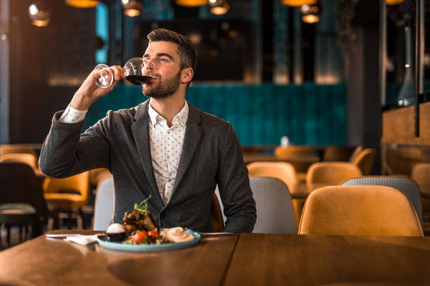 istock Happy man eating lunch at a restaurant and drinking red wine. 1372645431