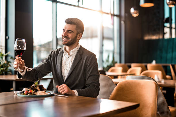 istock Happy man eating lunch at a restaurant and toasting with red wine. 1372645538