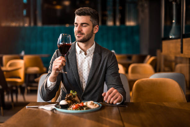 istock Happy man eating lunch at a restaurant and tasting red wine. 1372645545