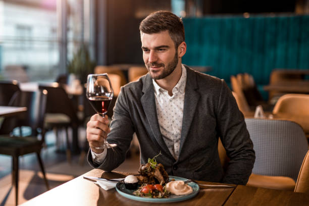 istock Happy man eating lunch at a restaurant and tasting beautiful red wine. 1372645574