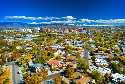 Downtown Albuquerque skyline aerial view with neighborhoods in the foreground and the Sandia Mountain Range in the background.  Photo was taken in autumn.
