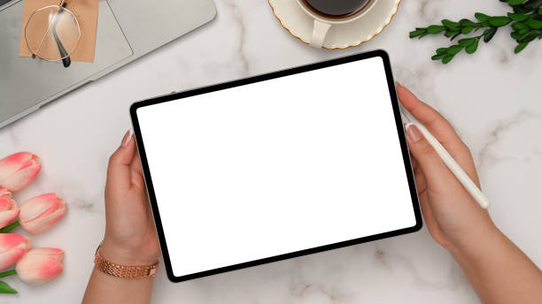 istock Female hands showing tablet white screen mockup over white marble background. 1372662167