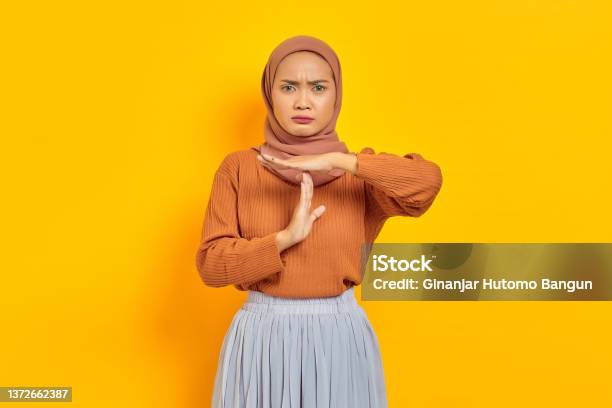 Beautiful Young Asian Woman In Brown Sweater And Hijab Showing Time Out Gesture With Hands Isolated Over Yellow Background People Islam Religious Concept Stock Photo - Download Image Now