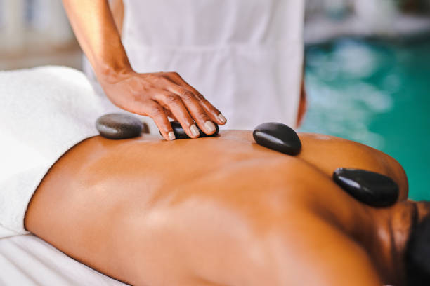 scatto di una donna che riceve un massaggio con pietre calde in una spa - lastone therapy spa treatment stone health spa foto e immagini stock