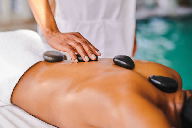 tiro de uma mulher recebendo uma massagem de pedra quente em um spa - lastone therapy massaging spa treatment stone - fotografias e filmes do acervo