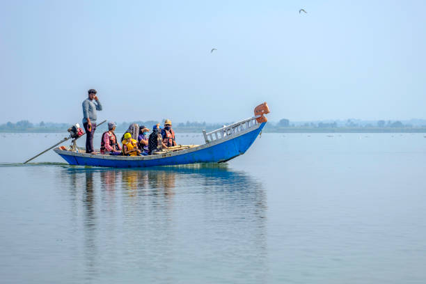 Mekong River, Luang Prabang, Laos - March 13th 2023: Slim river boat - almost a canoe - with two people and a load of green bananas
