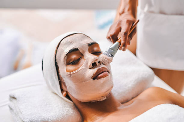 shot of an attractive young woman getting a facial at a beauty spa - masker stockfoto's en -beelden