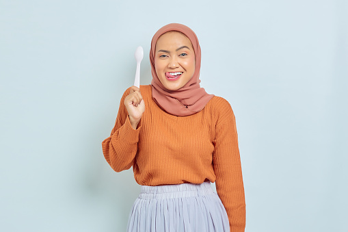 Beautiful young Asian woman in brown sweater licking lip want a delicious meal isolated over white background
