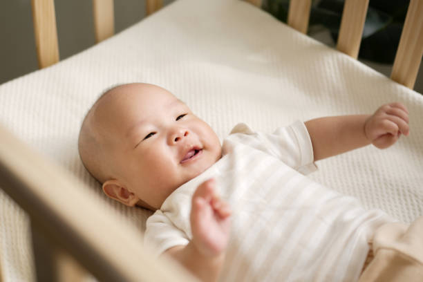 feliz bebé recién nacido asiático sonriendo y riendo en la cuna - cot fotografías e imágenes de stock