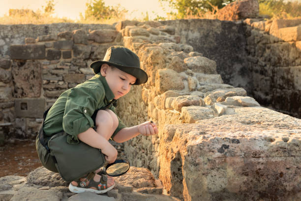 niño arqueólogo con ropa caqui estudiando las ruinas de una antigua ciudad. concepto de trabajo diverso y no tradicional - non rural scene fotografías e imágenes de stock