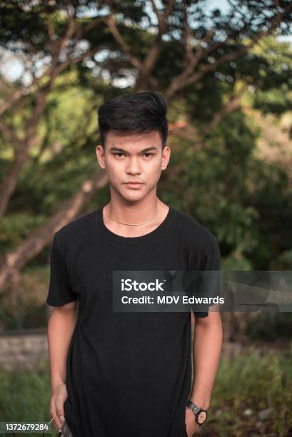 A Strikingly Handsome Young Filipino Man At The Park In A Black Tshirt At The Park During Late Afternoon Stock Photo - Download Image Now