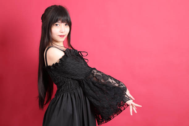 The teen Asian girl with cute gothic dressed standing on the red background.