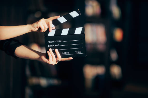 hände halten eine filmtafel, die eine filmszene inszeniert - filmklappe stock-fotos und bilder