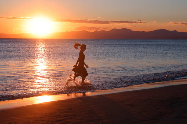 istock Beautiful young woman running at sunset beach 1372682835