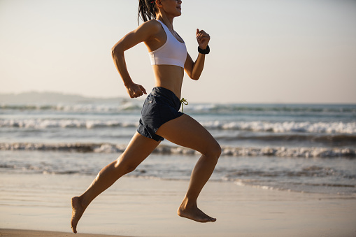 Fitness woman running on beach