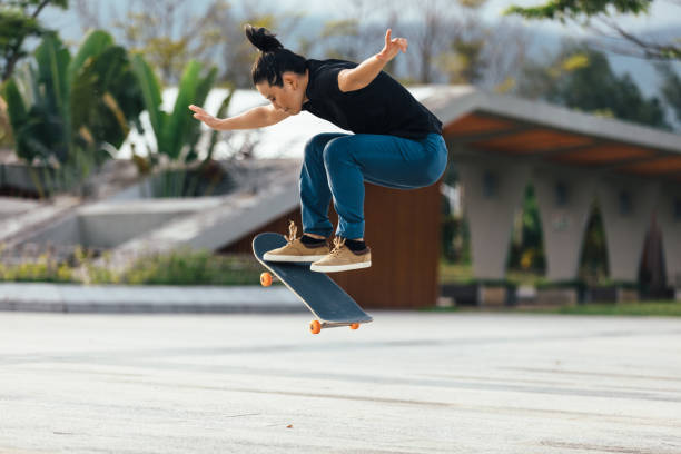 азиатская женщина скейтбордист скейтбординг в современном городе - skateboarding skateboard extreme sports sport стоковые фото и изображения