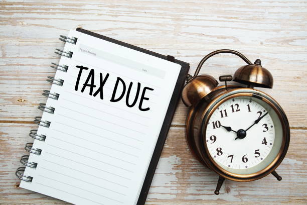 istock Tax due text on notepad with alarm clock on wooden background 1372691633