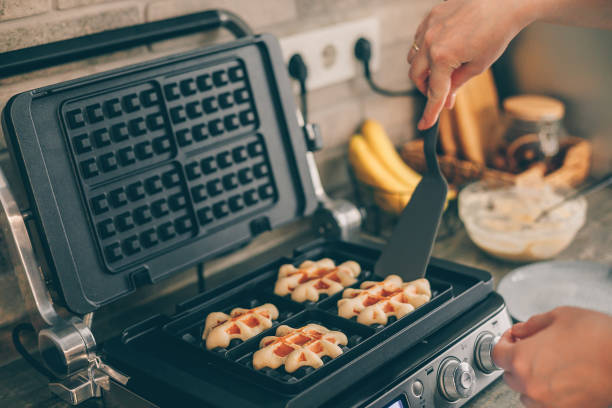 istock Young woman preparing Belgian waffles in the kitchen. Cooking process 1372696042