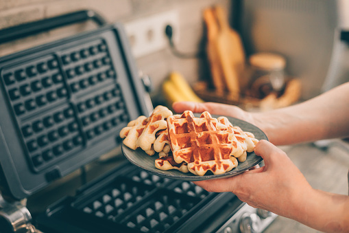 Young woman holding in hands plate with Belgian waffles.