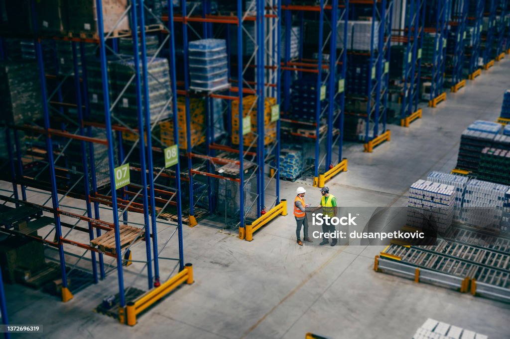 A businessman introducing himself to his worker at storage. A businessman and worker shaking hands at warehouse. Warehouse Stock Photo