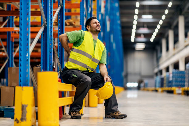 A warehouse worker having back pain and rubbing it. stock photo