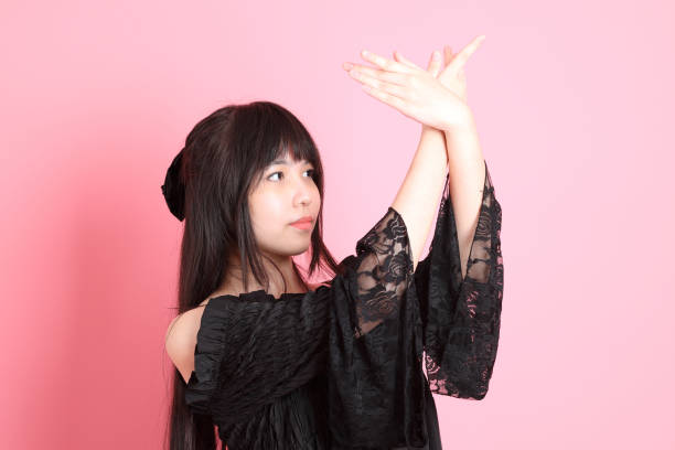 The cute young Asian girl with gothic dressed standing on the pink background