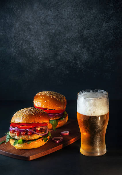 glass of foamy alcoholic drink beer and hamburgers stock photo