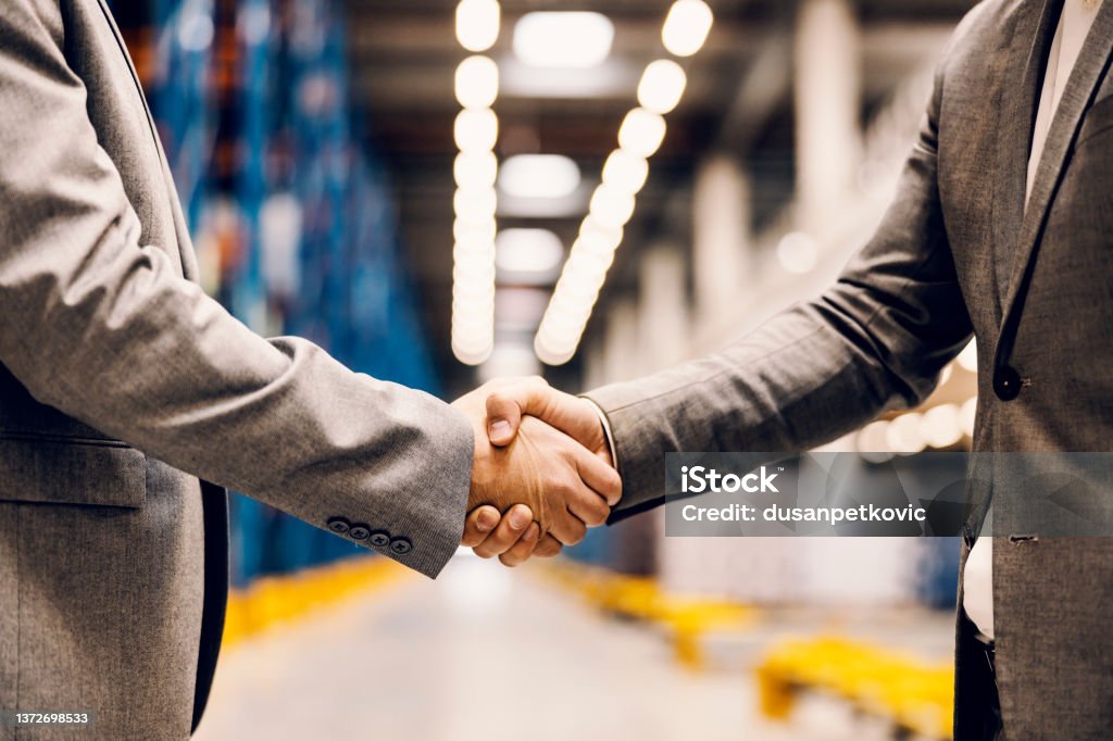 Close up of a handshake of business partners at storage. Close up of a business partners shaking hands at warehouse. Handshake Stock Photo
