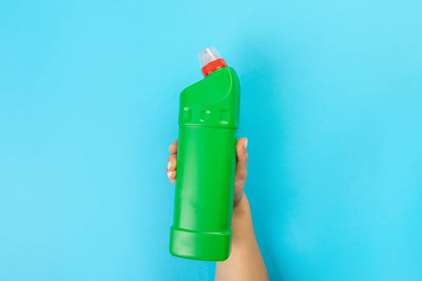 istock Housewife's hand holds a spray with cleaning agent on a blue background. Detergent for various surfaces in the kitchen, bathroom and other rooms. Close-up. Light pastel blue background. 1372699219