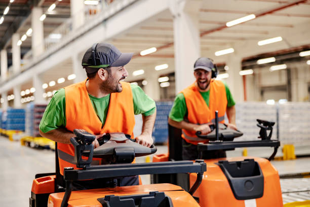 istock Two warehouse workers race with forklift and having fun at workplace. 1372699948
