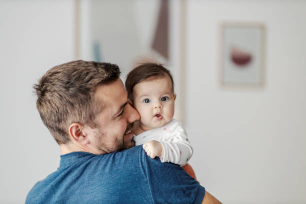 un bébé confus dans les bras du père regardant la caméra et faisant des grimaces. - père photos et images de collection