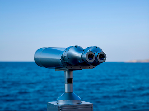 The telescope stands on the bank of River. The pipe is in focus, and the shore opposite is out of focus.