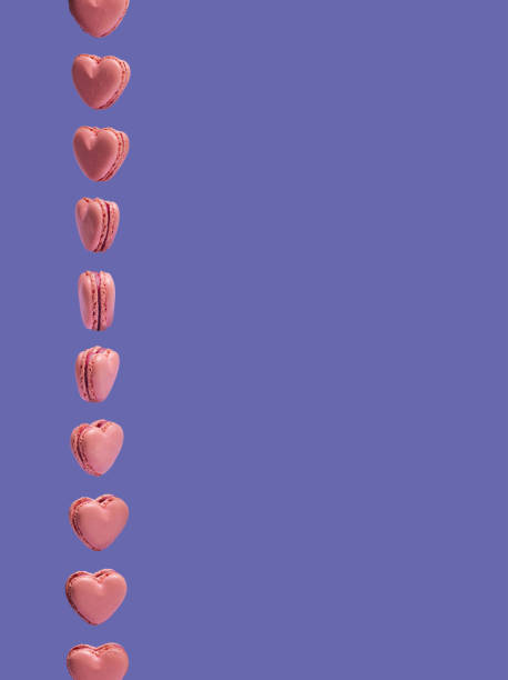 istock Pink heart shaped macarons rotate vertically. Creative copy space against very peri background. Artisans love the patisserie concept. 1372706657