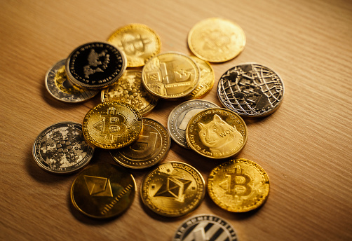 Antalya, Turkey - February 12, 2022: Close up shot of Bitcoin and alt coins cryptocurrency over brown background