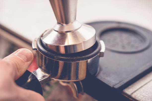 barista falsifiant le café dans portafilter en utilisant tamper. processus de préparation du café frais en gros plan - tampering photos et images de collection