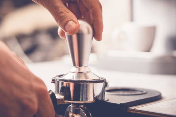 barista falsifiant le café dans portafilter en utilisant tamper. processus de préparation du café frais en gros plan - tampering photos et images de collection