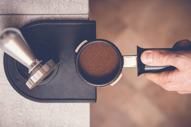 barista falsifiant le café dans portafilter en utilisant tamper. processus de préparation du café frais en gros plan - tampering photos et images de collection