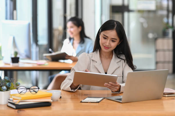 istock Attractive asian woman office worker searching information on digital tablet. 1372712302