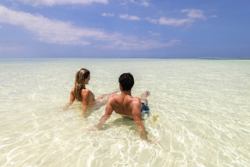 Rear view of a couple relaxing in sea during summertime. Copy space.