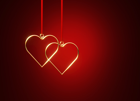 Heart shapes hanging from red ribbons over red background.  Horizontal composition with copy space.